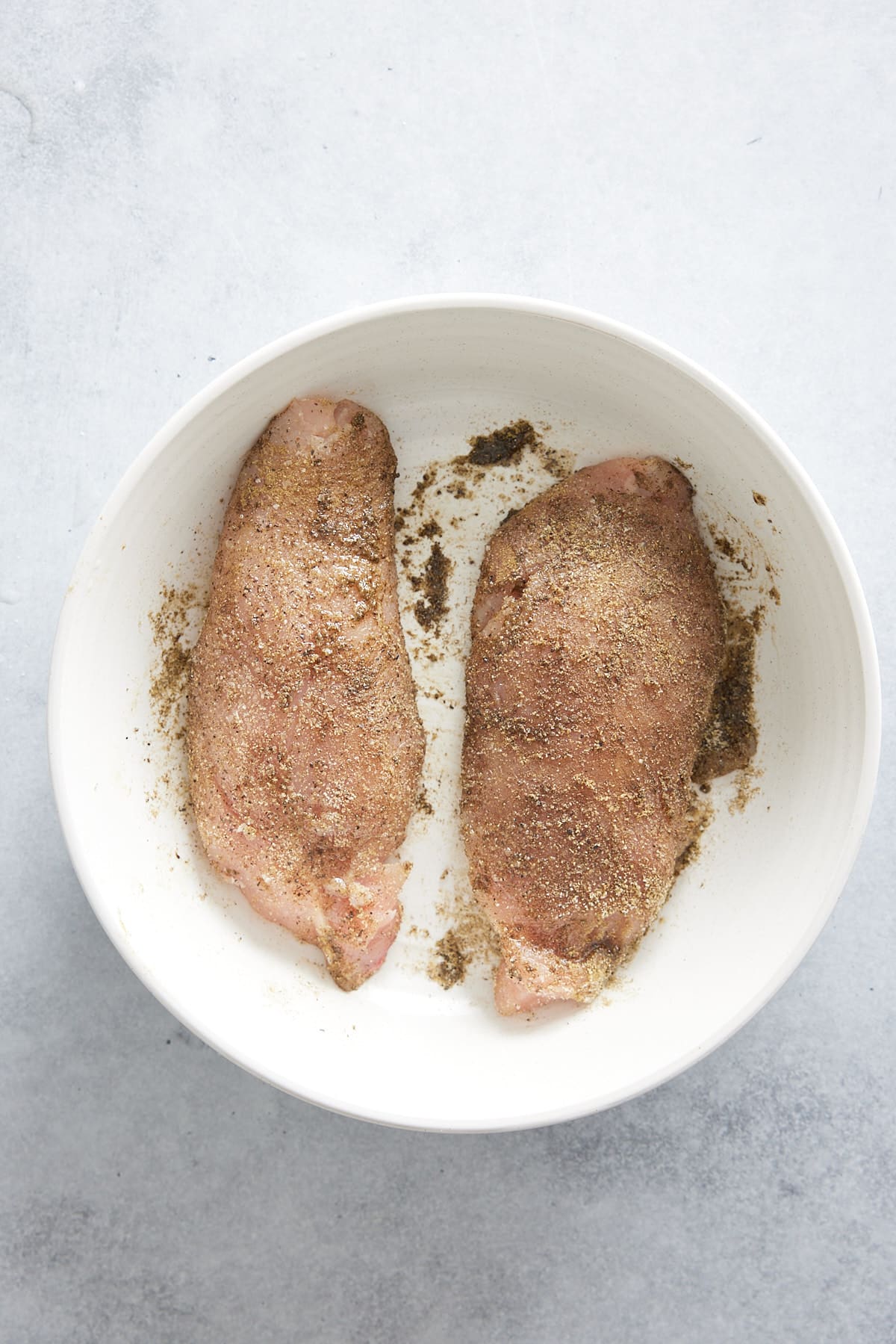 Two seasoned turkey tenderloins set into a white bowl