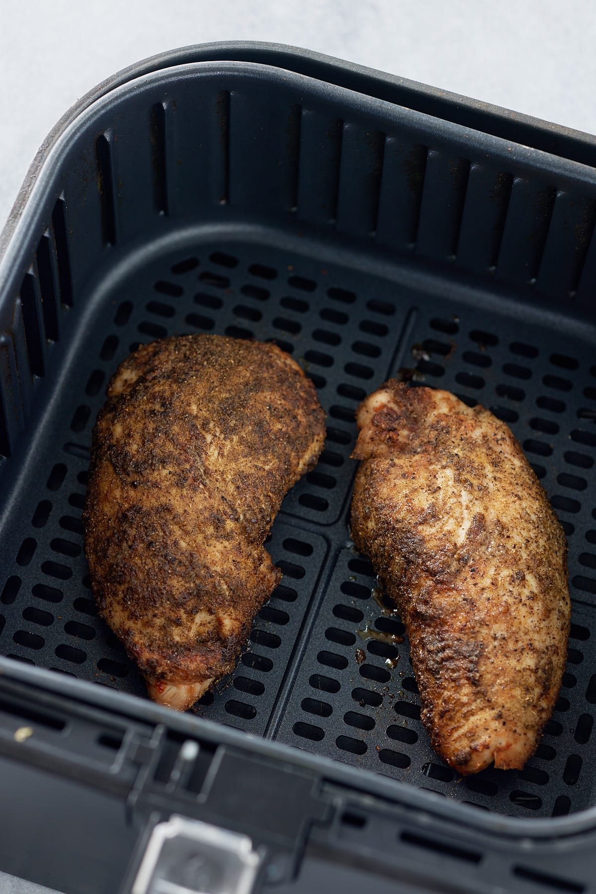 Two cooked turkey tenderloins set into air fryer basket