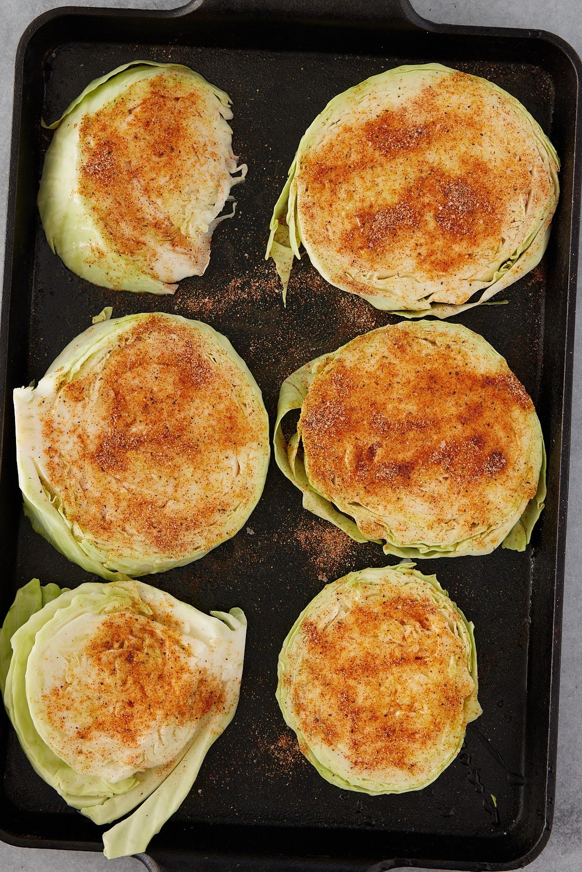 6 seasoned cabbage steaks on a baking sheet