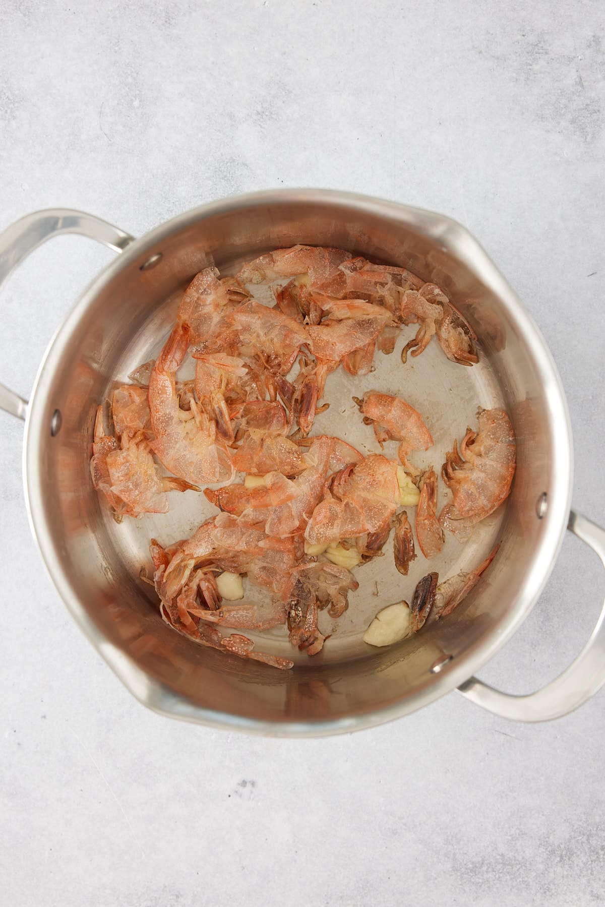 Stock pot containing sauted shrimp shells, oil and garlic