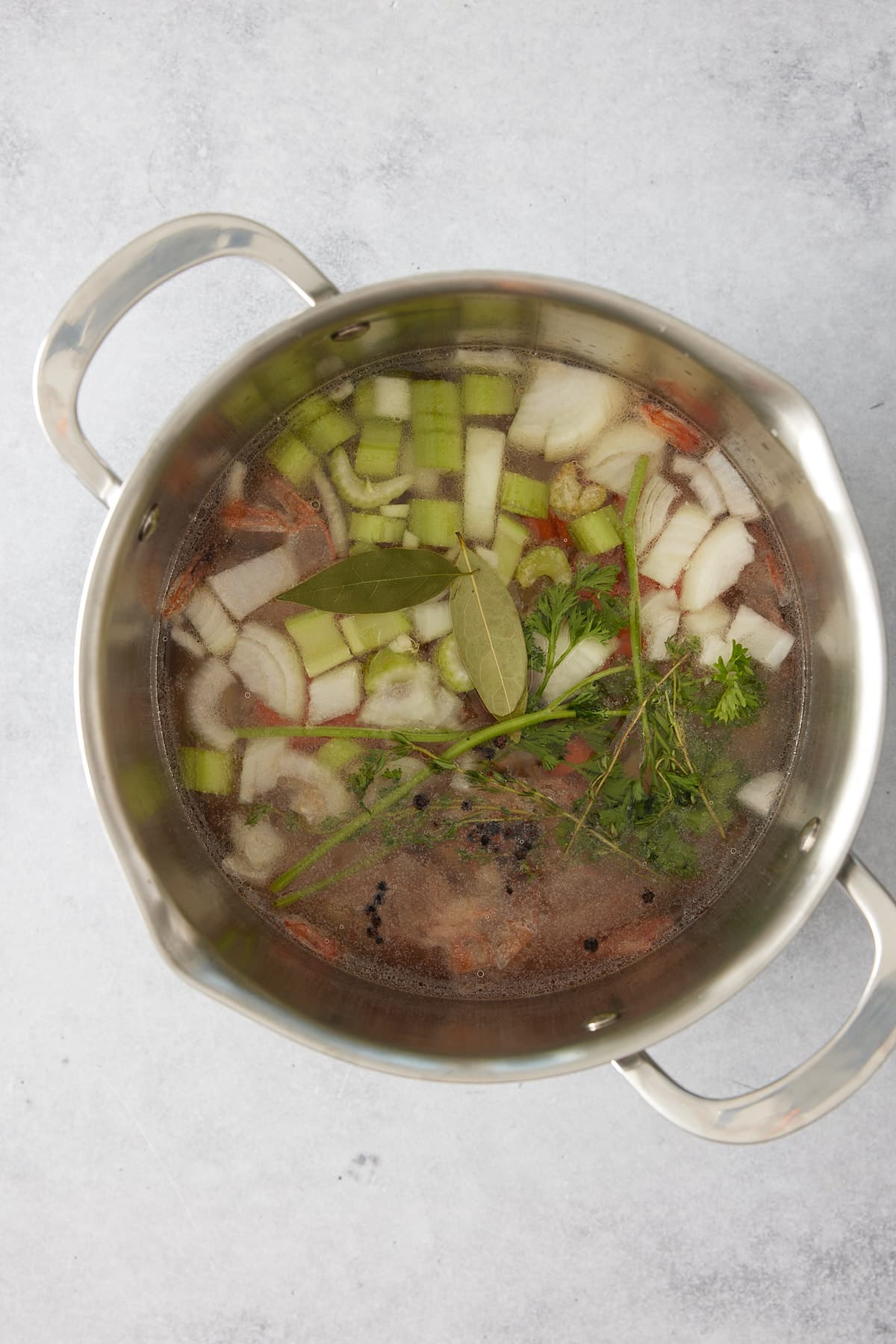 Stock pot containing raw ingredients for shrimp stock