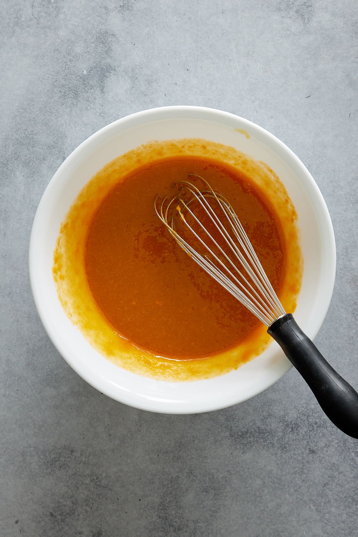 a large bowl of brown sugar, eggs, oil and mashed sweet potato whisked together.