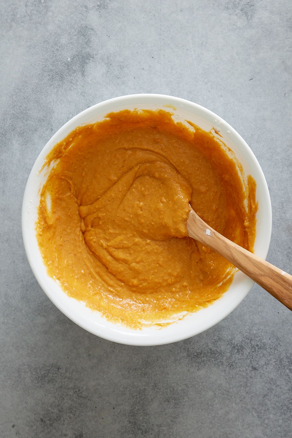 dry and wet ingredients combined in a large bowl with a wooden spoon