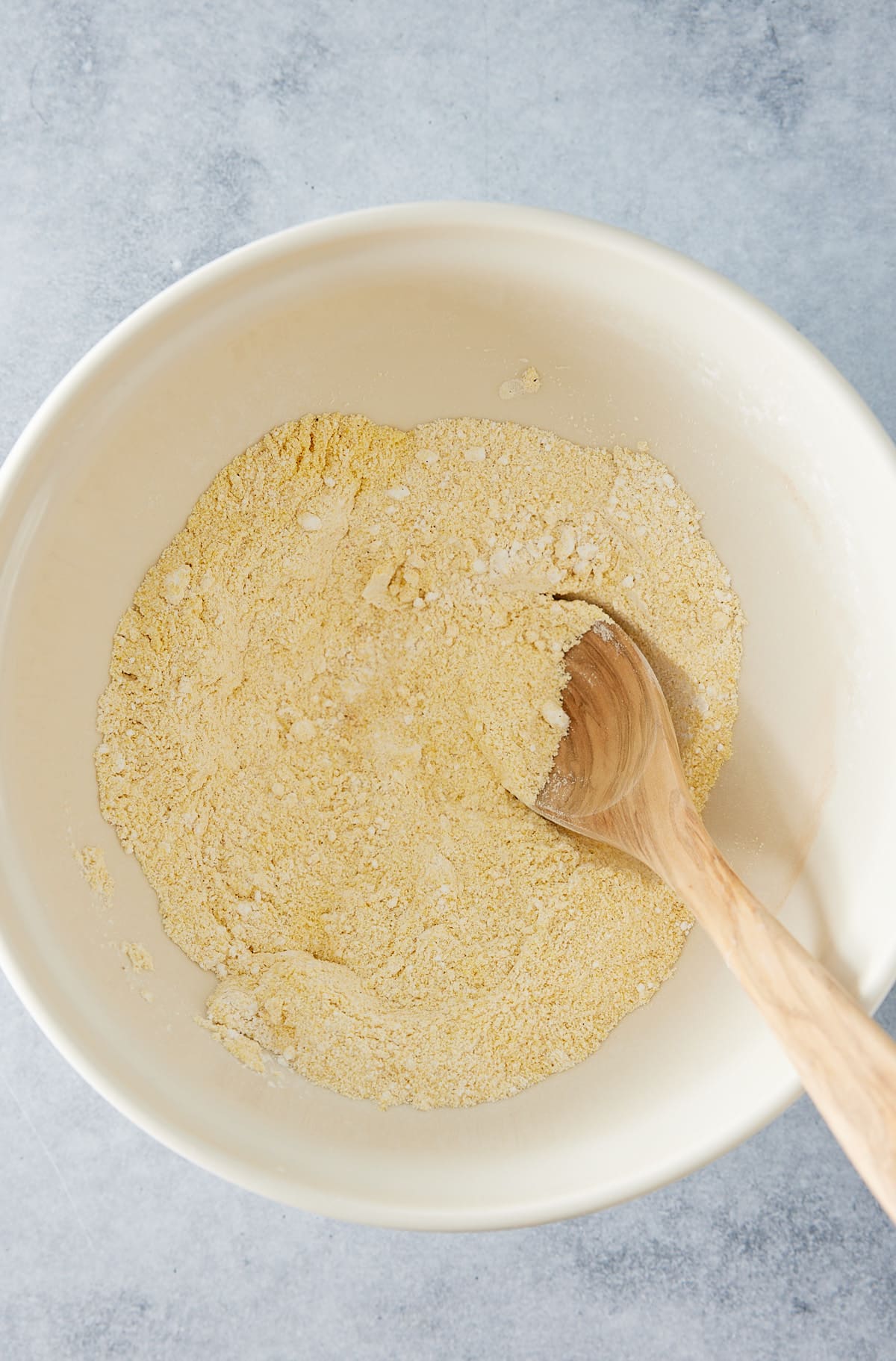 Large white mixing bowl filled with cornmeal and flour