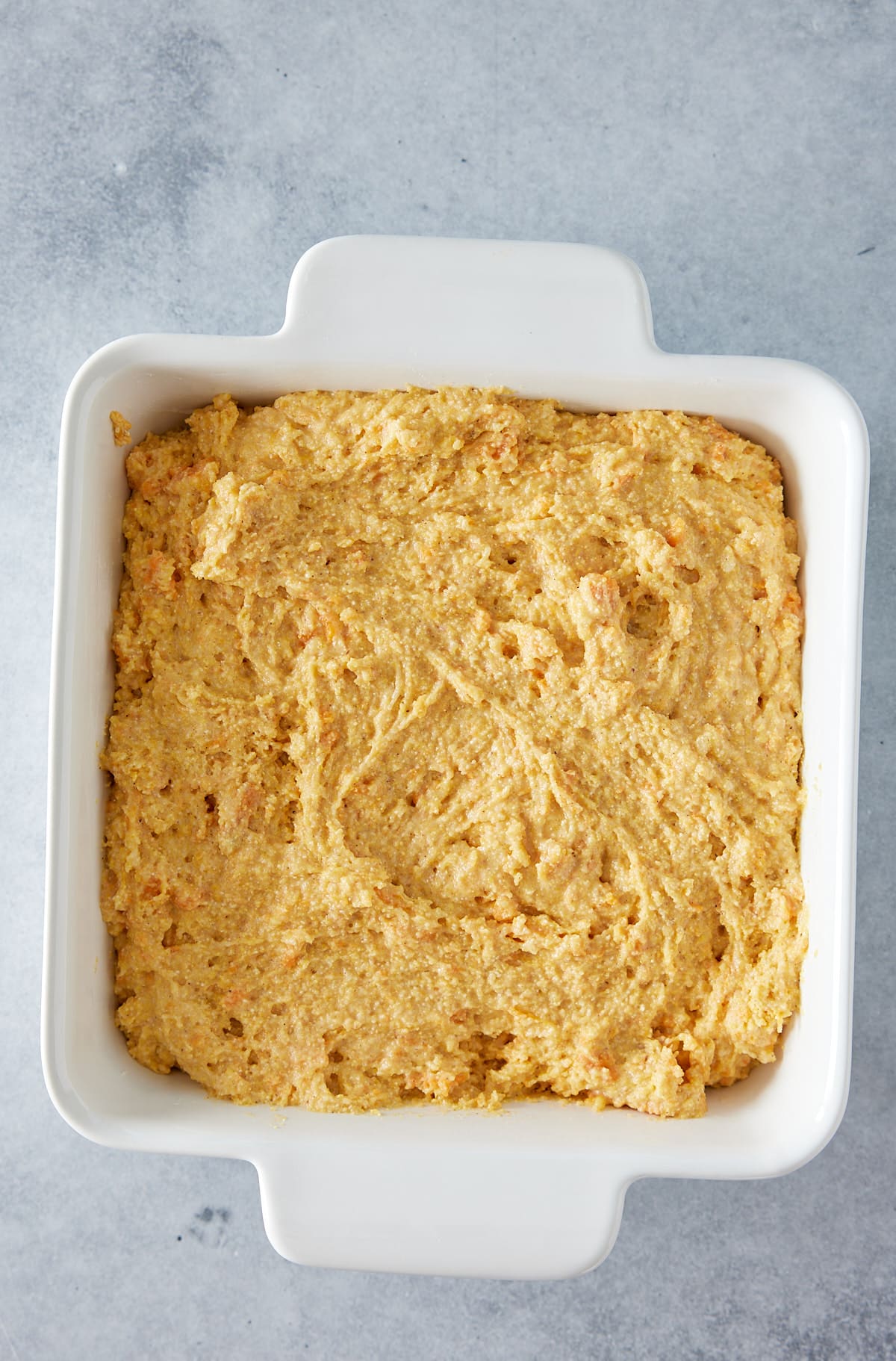 White square oven proof dish filled with cornbread batter
