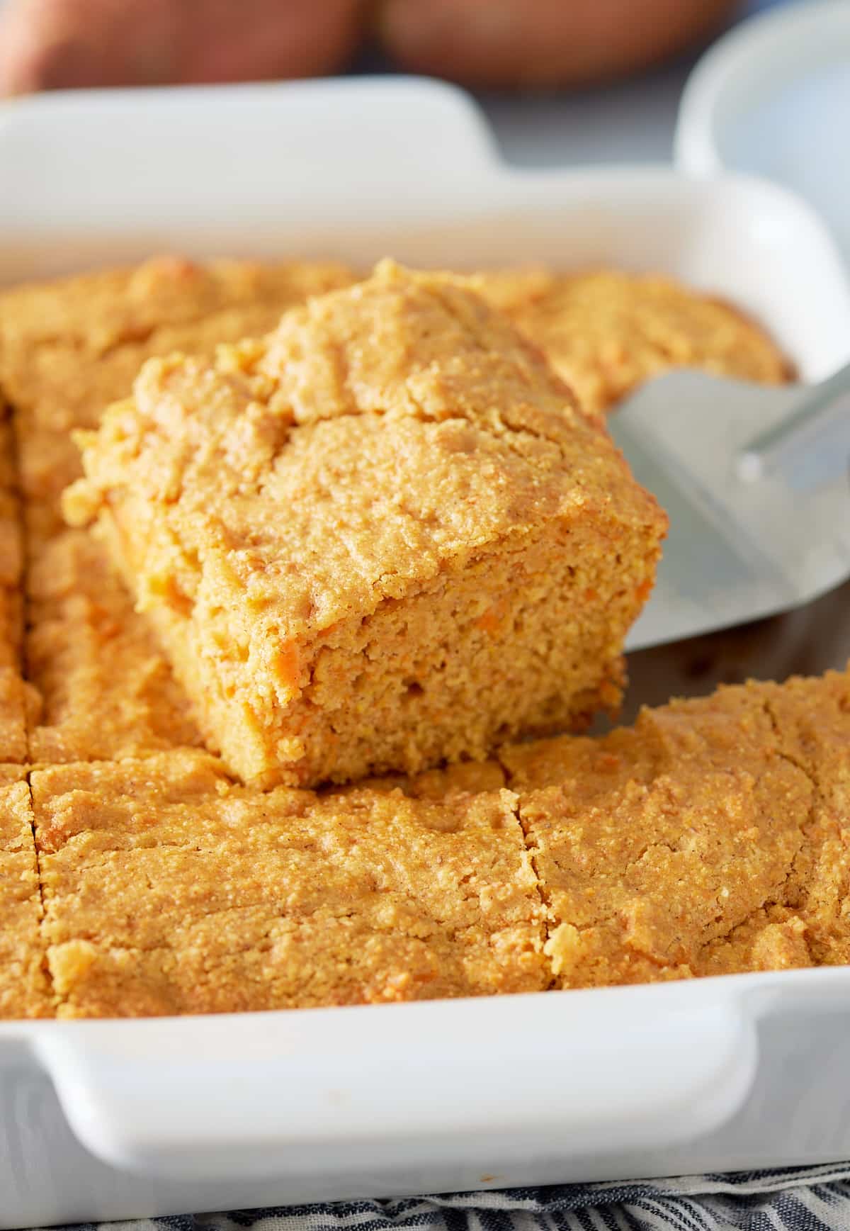 Close up image of slice of sweet potato cornbread being cut from dish