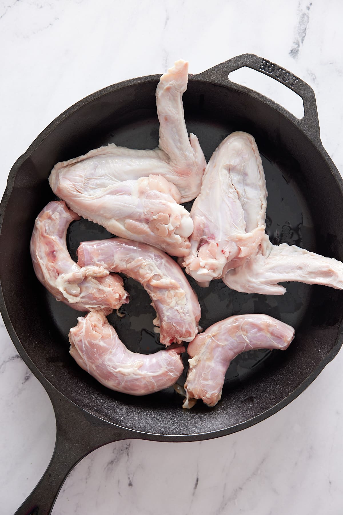 Cast iron skillet with raw turkey wings and neck