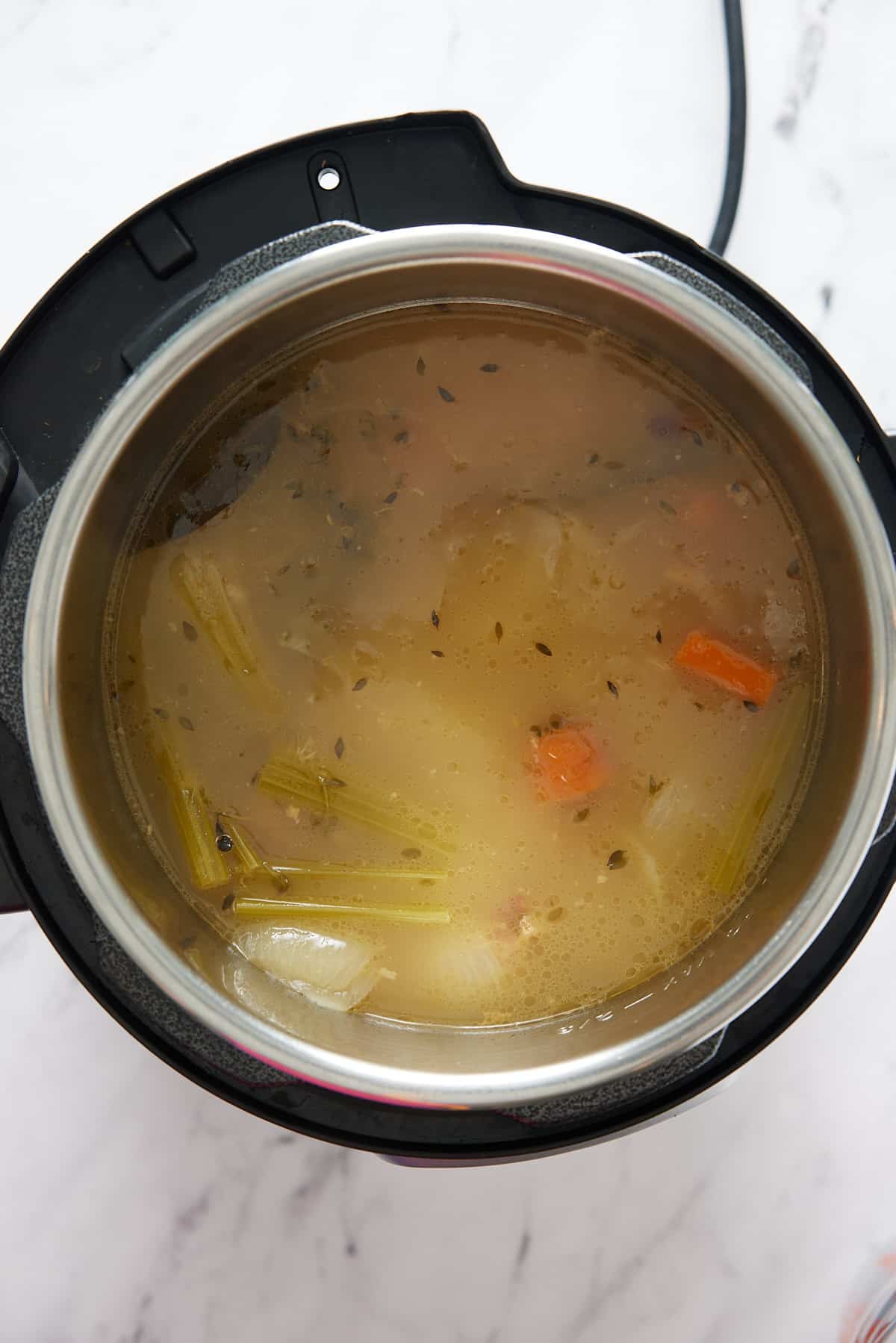 Pressure cooker pot containing cooked turkey broth