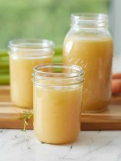 3 jars filled with turkey broth set on a wooden board