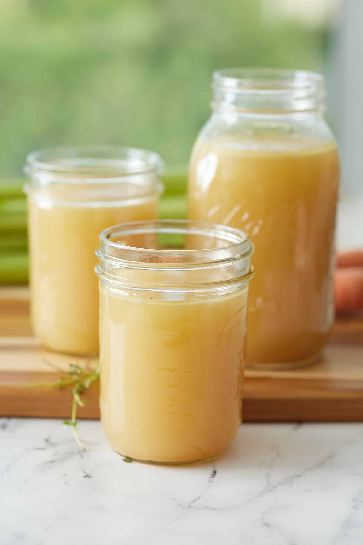 3 jars filled with turkey broth set on a wooden board