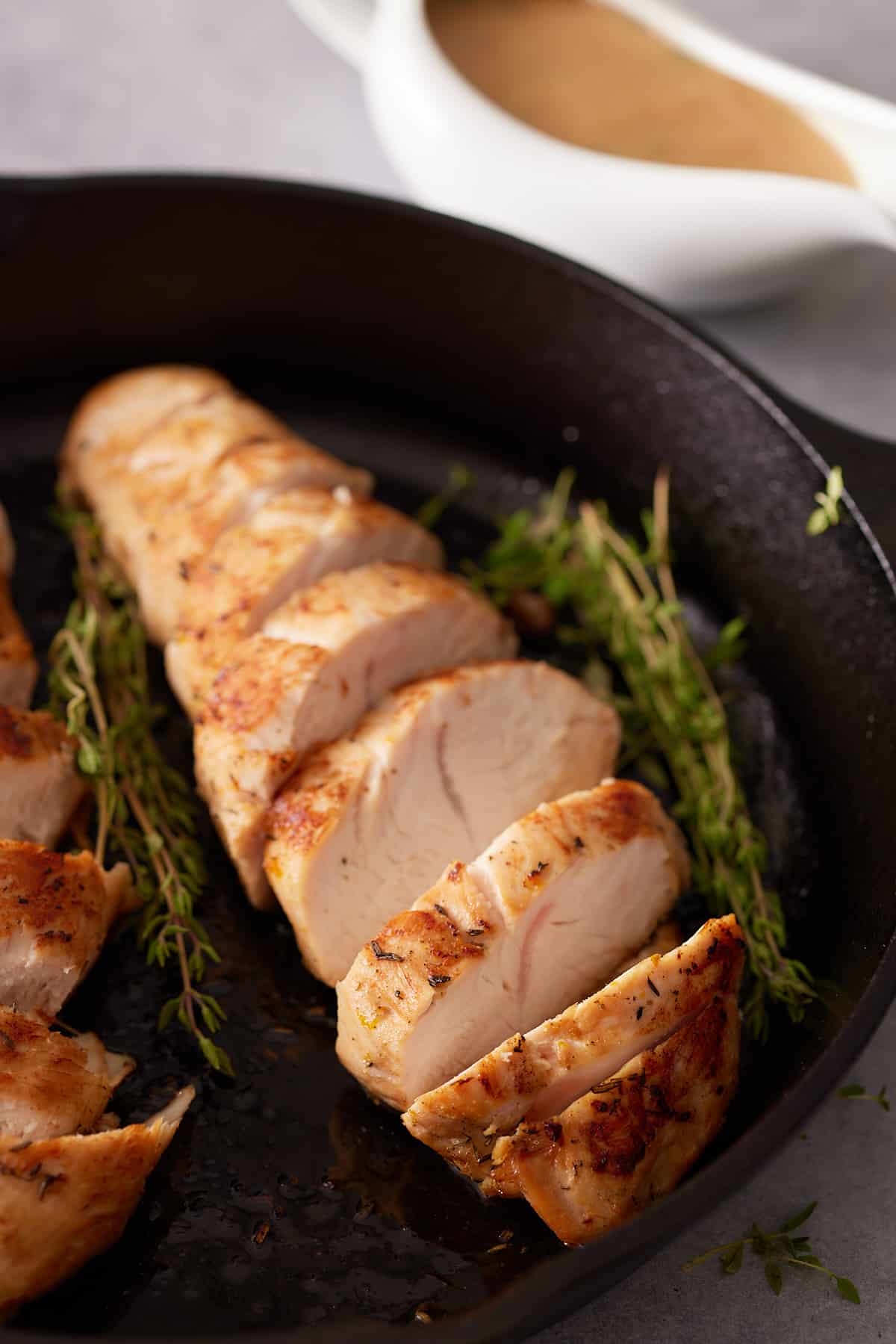 Cast iron skillet containing cooked and sliced turkey tenderloins.