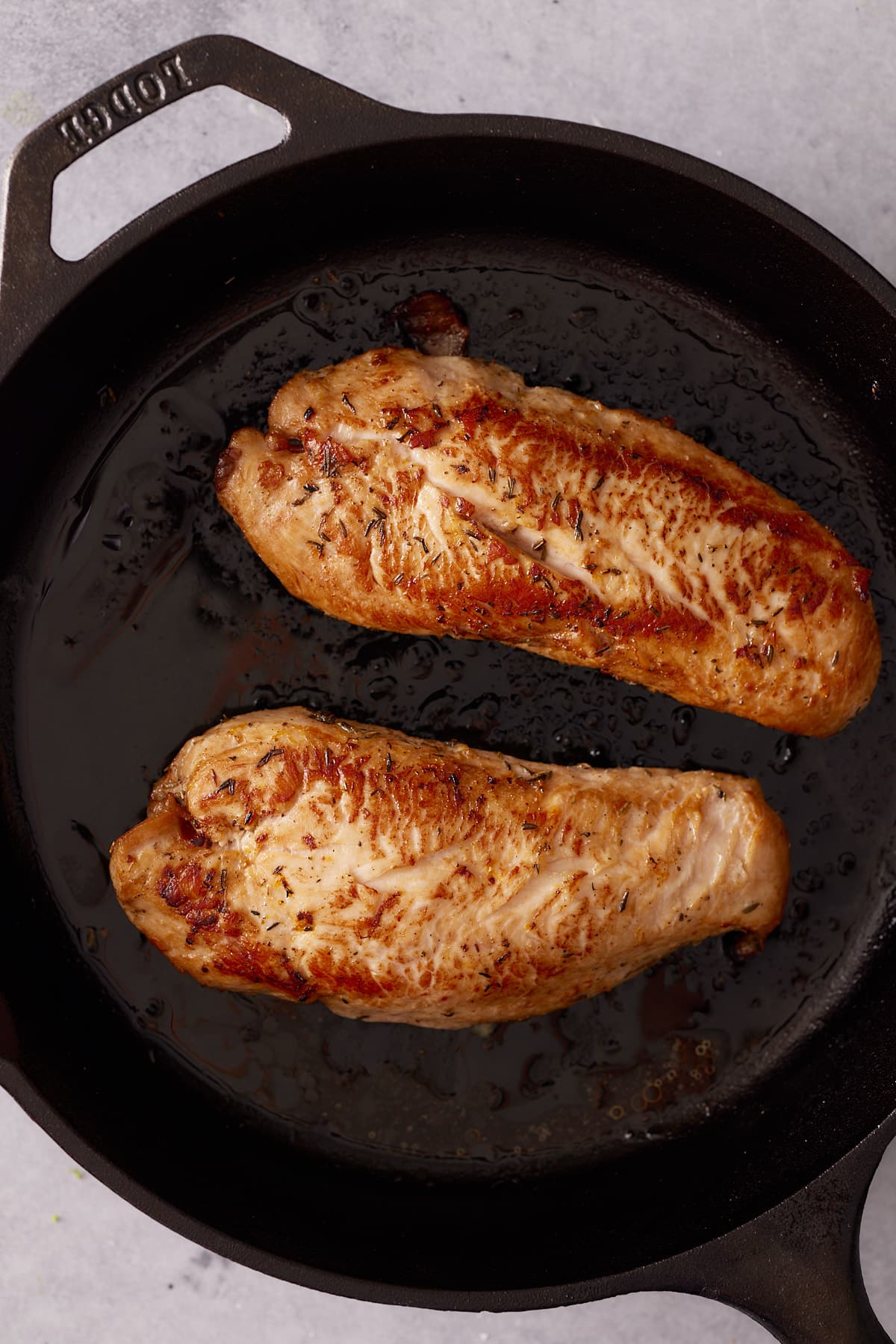 Two turkey tenderloins seared in a cast iron skillet