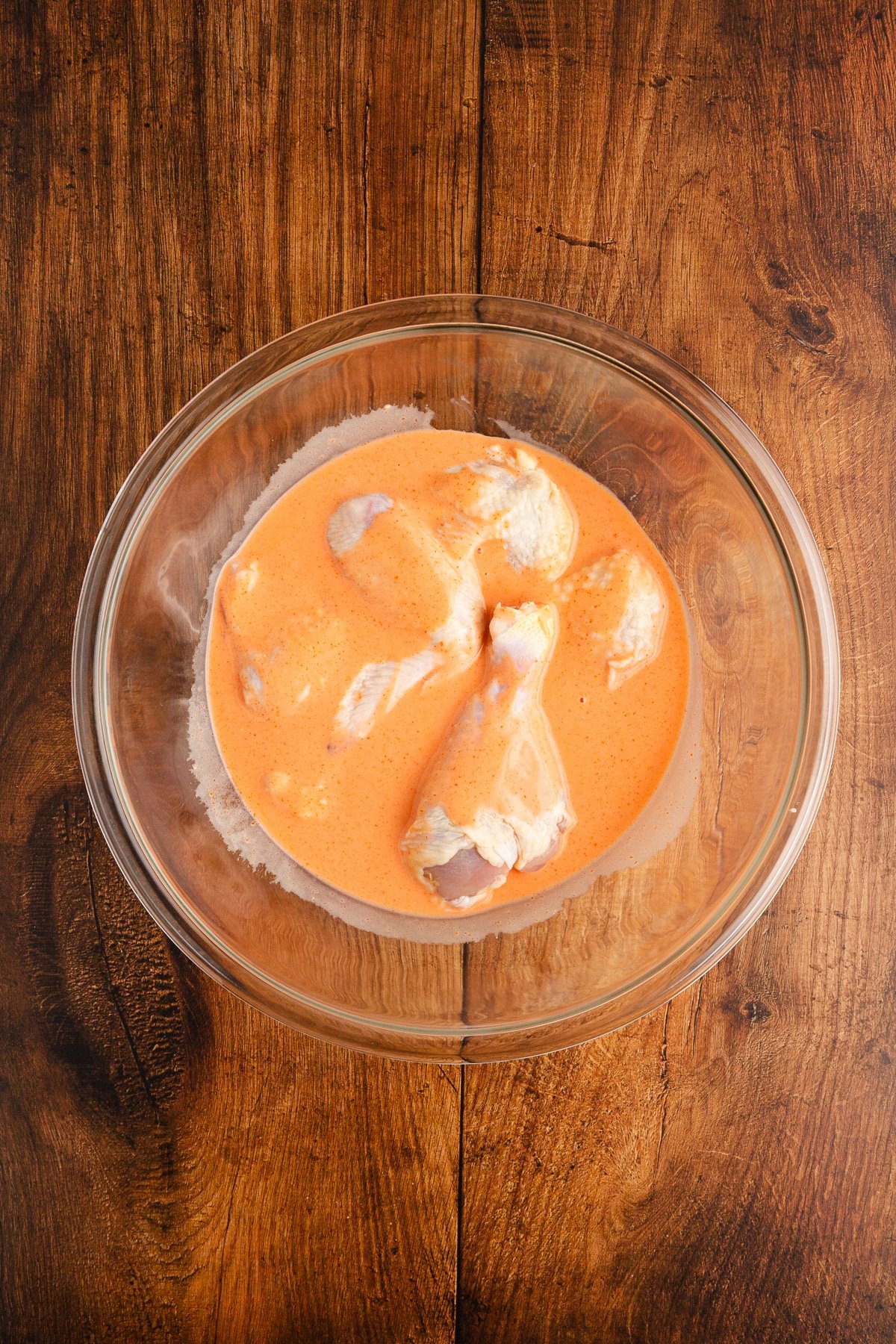 Raw chicken soaking in hot sauce and buttermilk. 