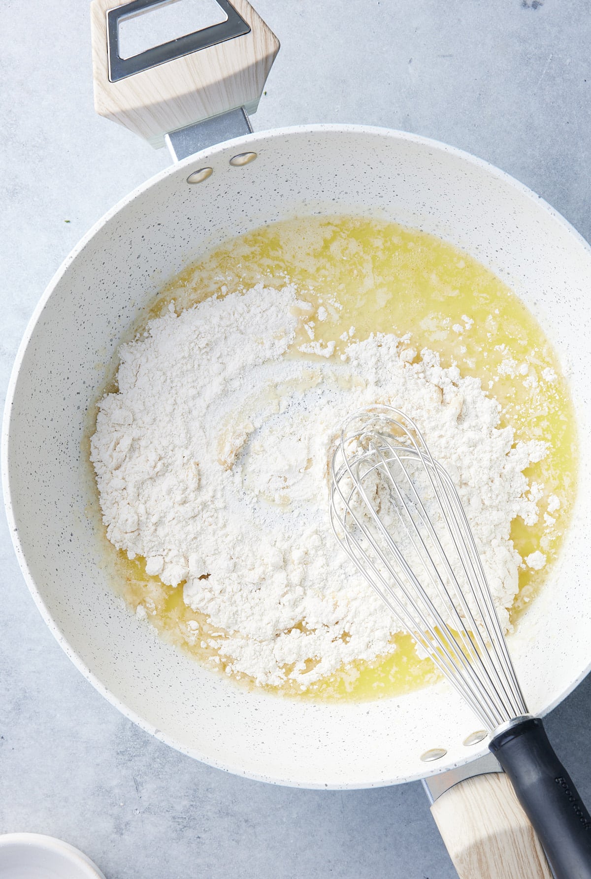 Large skillet with flour being whisked into melted butter