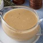 A glass gravy jug filled with brown gravy