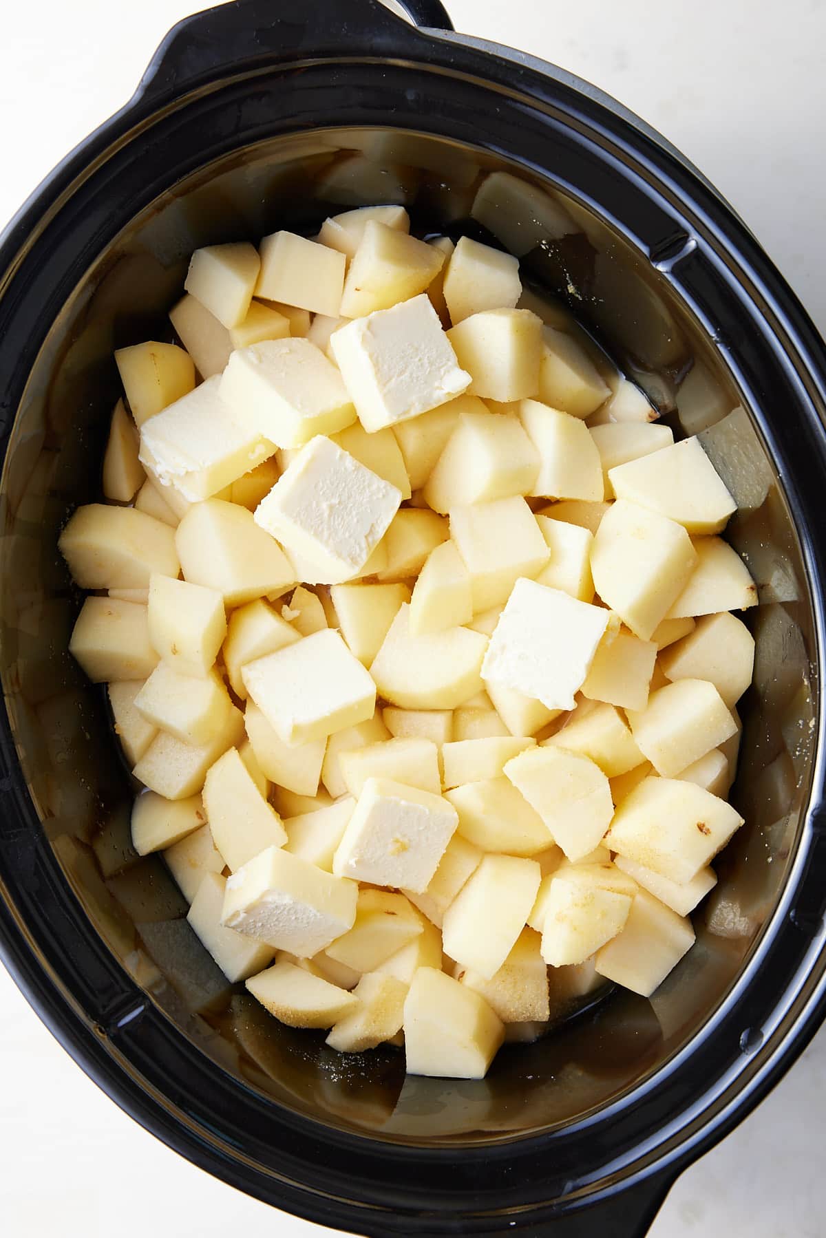 cubed potatoes in a slow cooker with butter on top