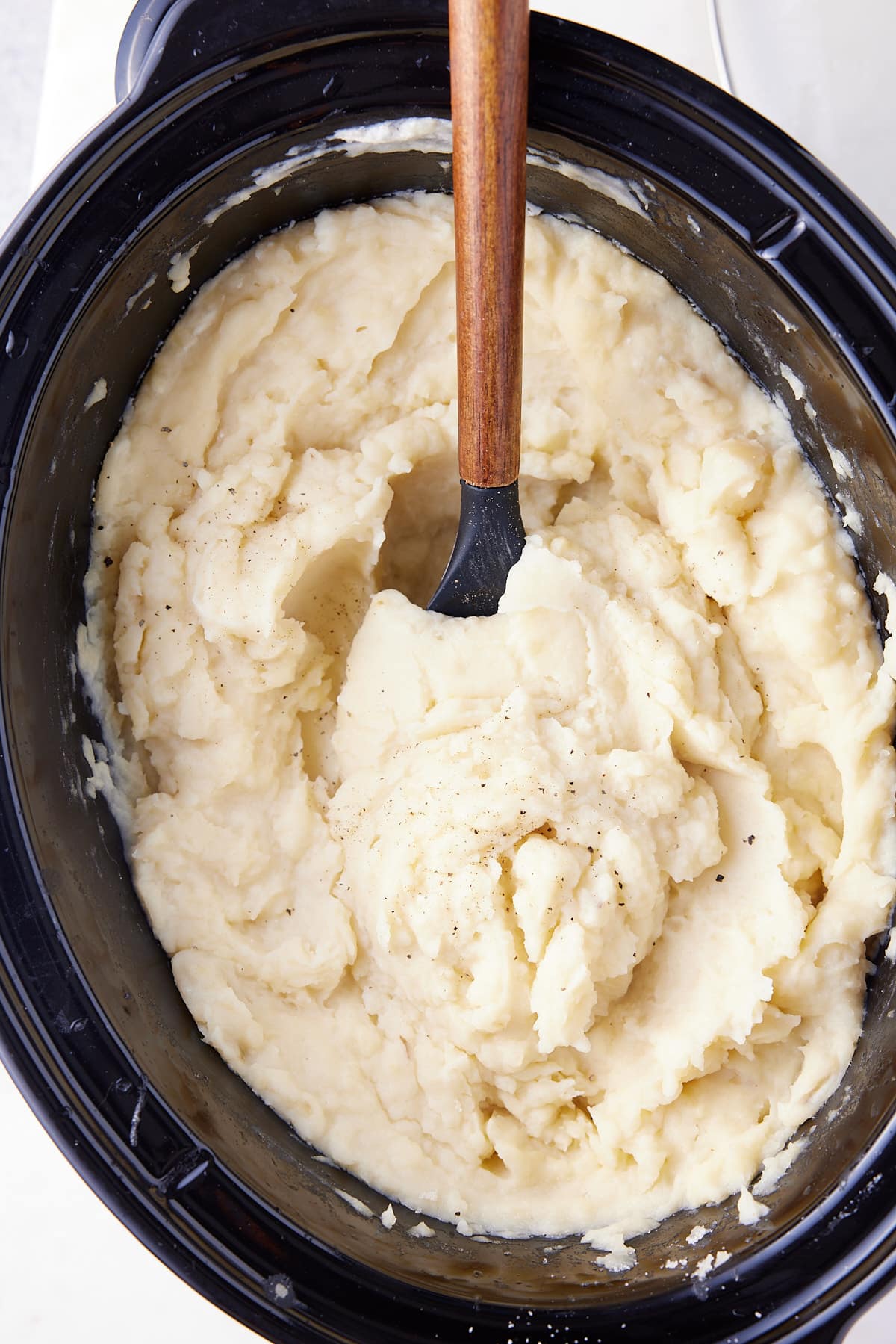 mashed potatoes in slow cooker with spoon sticking out