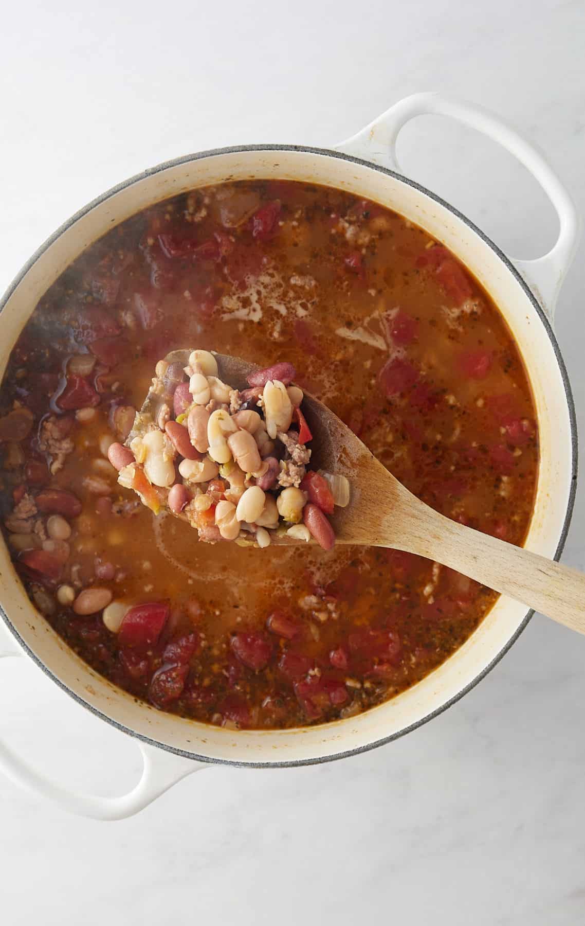 Cooked 15-bean soup with a wooden spoon showing that it's done