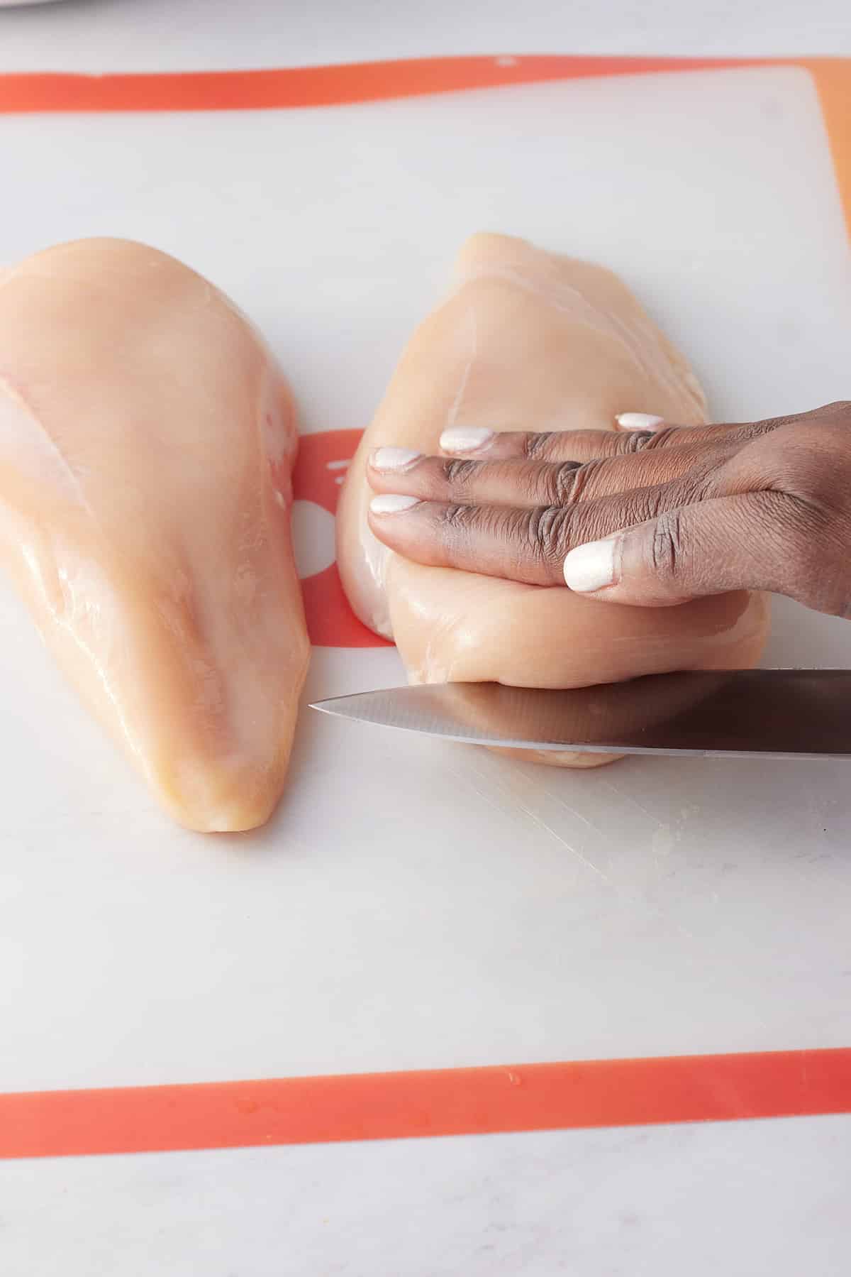 hand slicing the chicken breast in half
