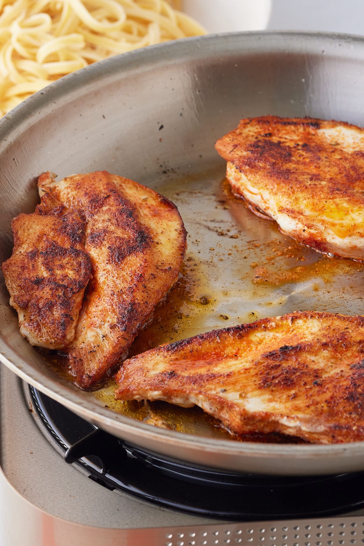 seasoned chicken being cooked in a pan