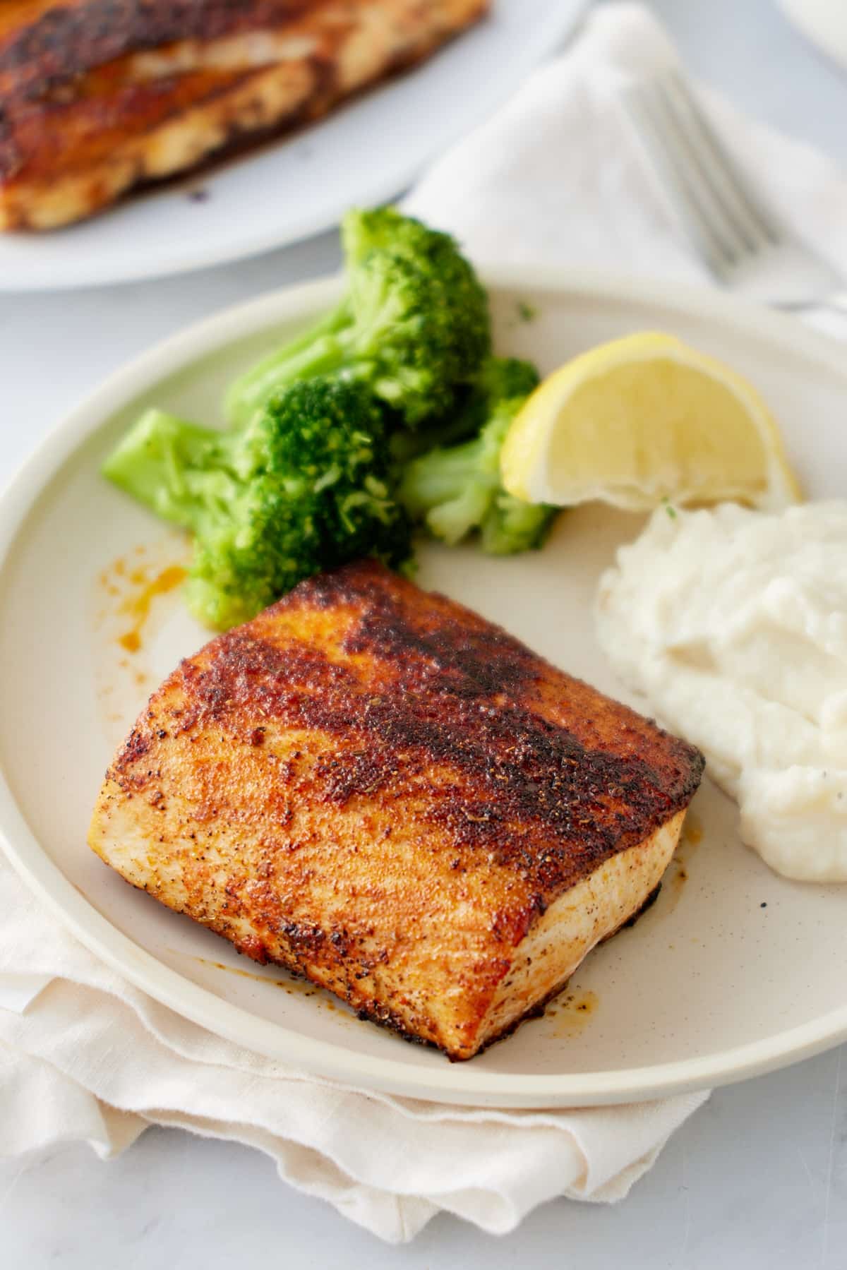 blackened mahi mahi on a plate with broccoli an mashed potatoes