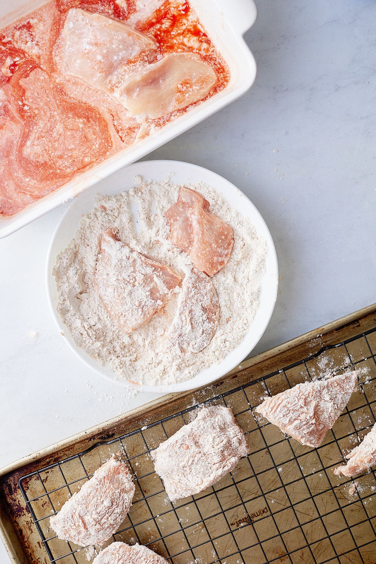 chicken pieces being dredged in flour