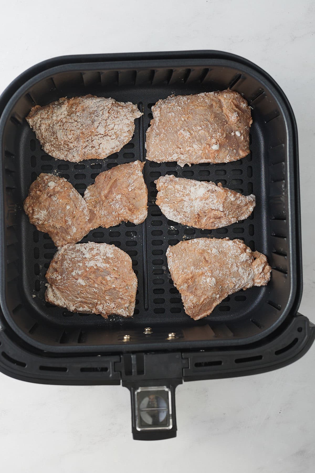 raw chicken pieces in air fryer basket