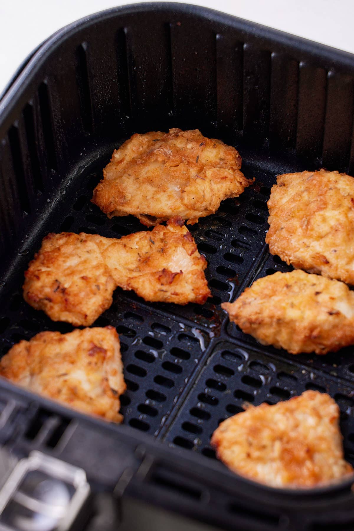 cooked fried chicken pieces in air fryer basket