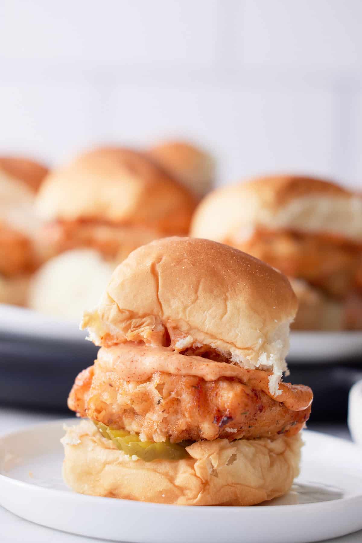 fried chicken slider on plate with other sandwiches in background