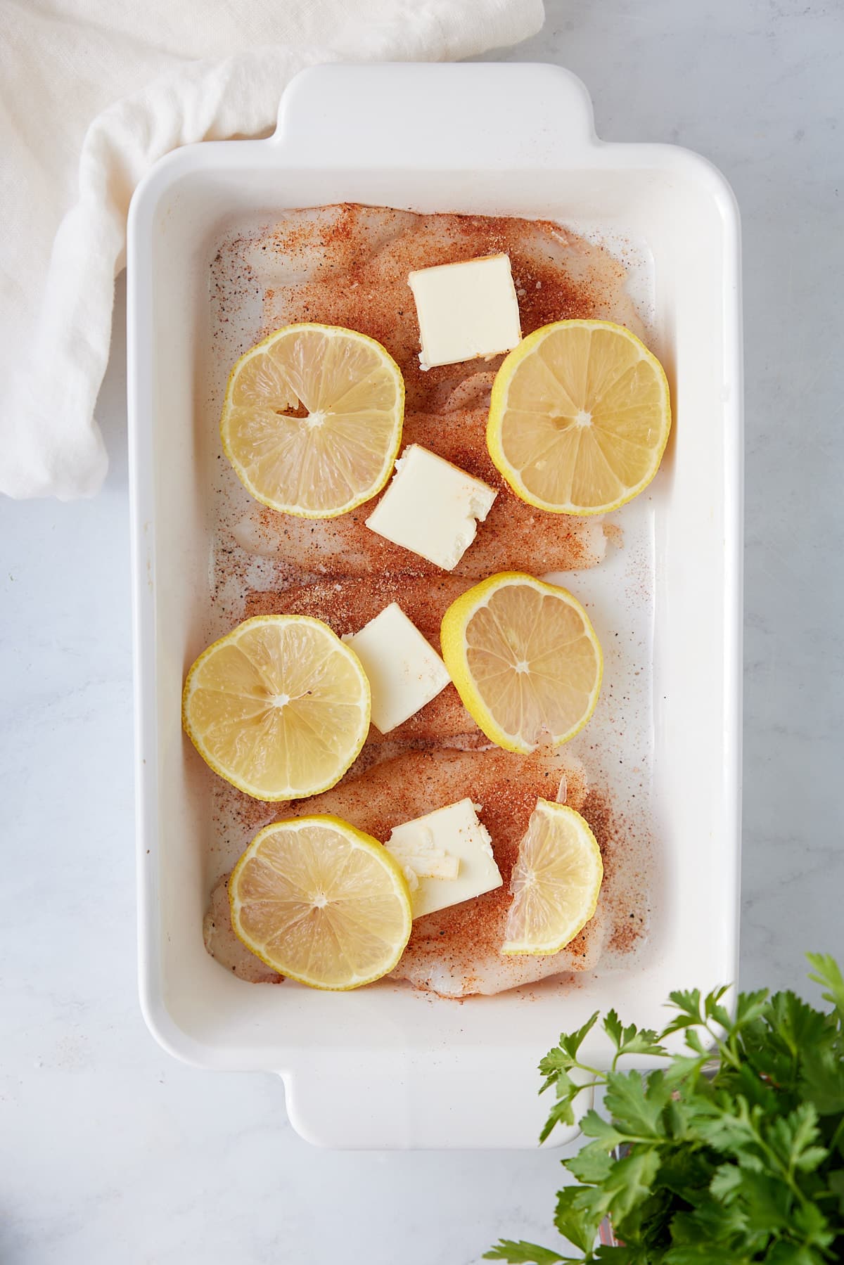cod prepared in the baking dish with butter slices and sliced lemons