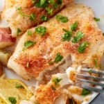 oven baked cod being cut by a fork