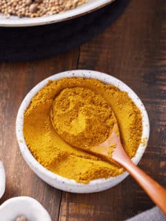 jamaican curry powder in bowl with spoon sticking out