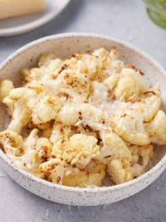 bowl filled with roasted air fryer cauliflower garnished with shredded Parmesan cheese