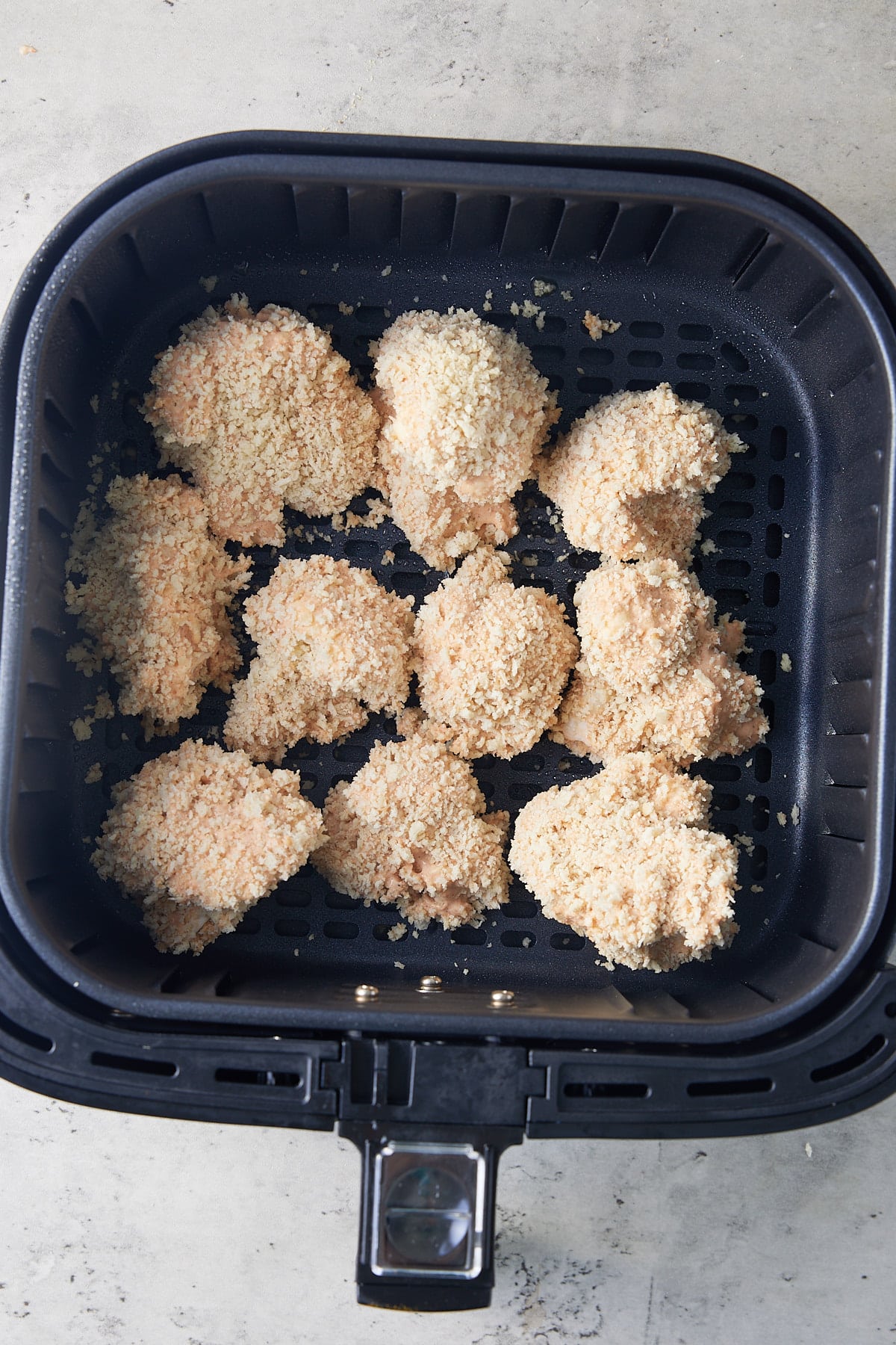 uncooked, breaded cauliflower florets in air fryer basket