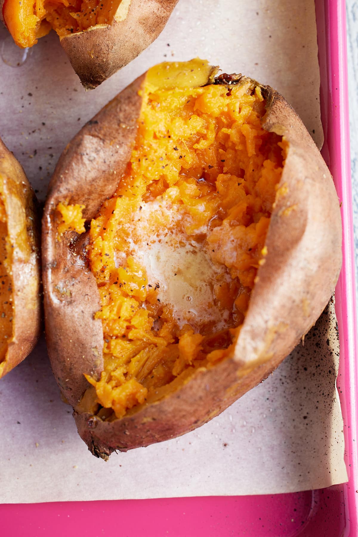 close up image of baked sweet potato topped with melted butter and salt and pepper