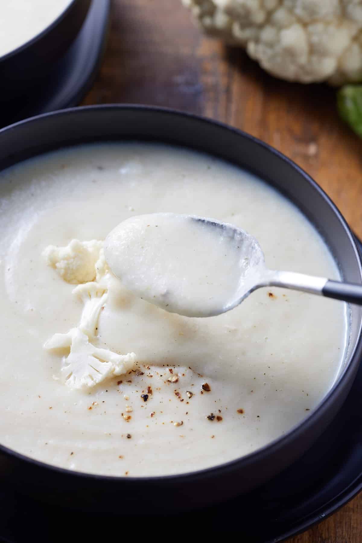 a bowl of cauliflower soup with a spoon in it