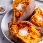 three cooked sweet potatoes on a plate topped with butter