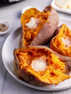 three cooked sweet potatoes on a plate topped with butter