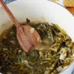 turnip greens in a pot with a wooden spoon