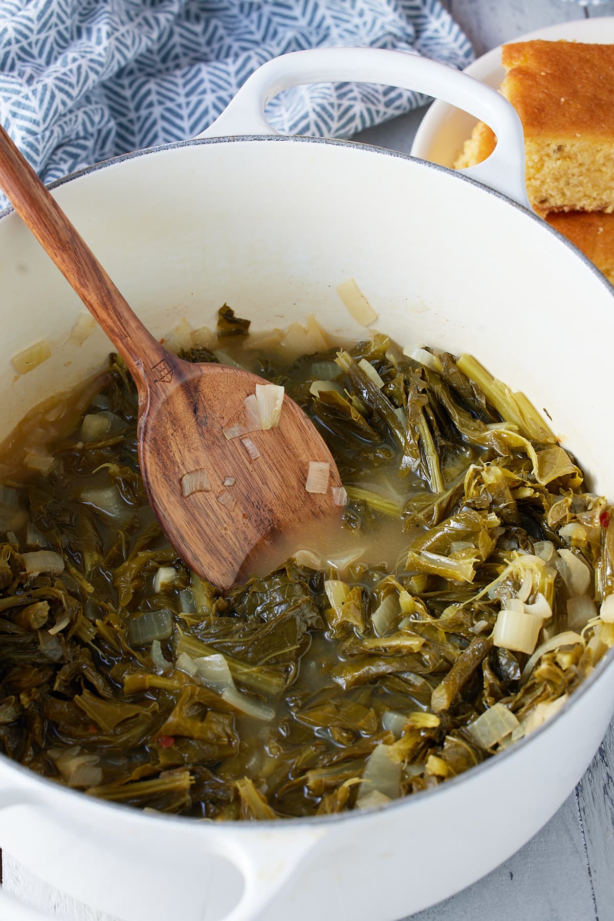turnip greens in a pot with a wooden spoon