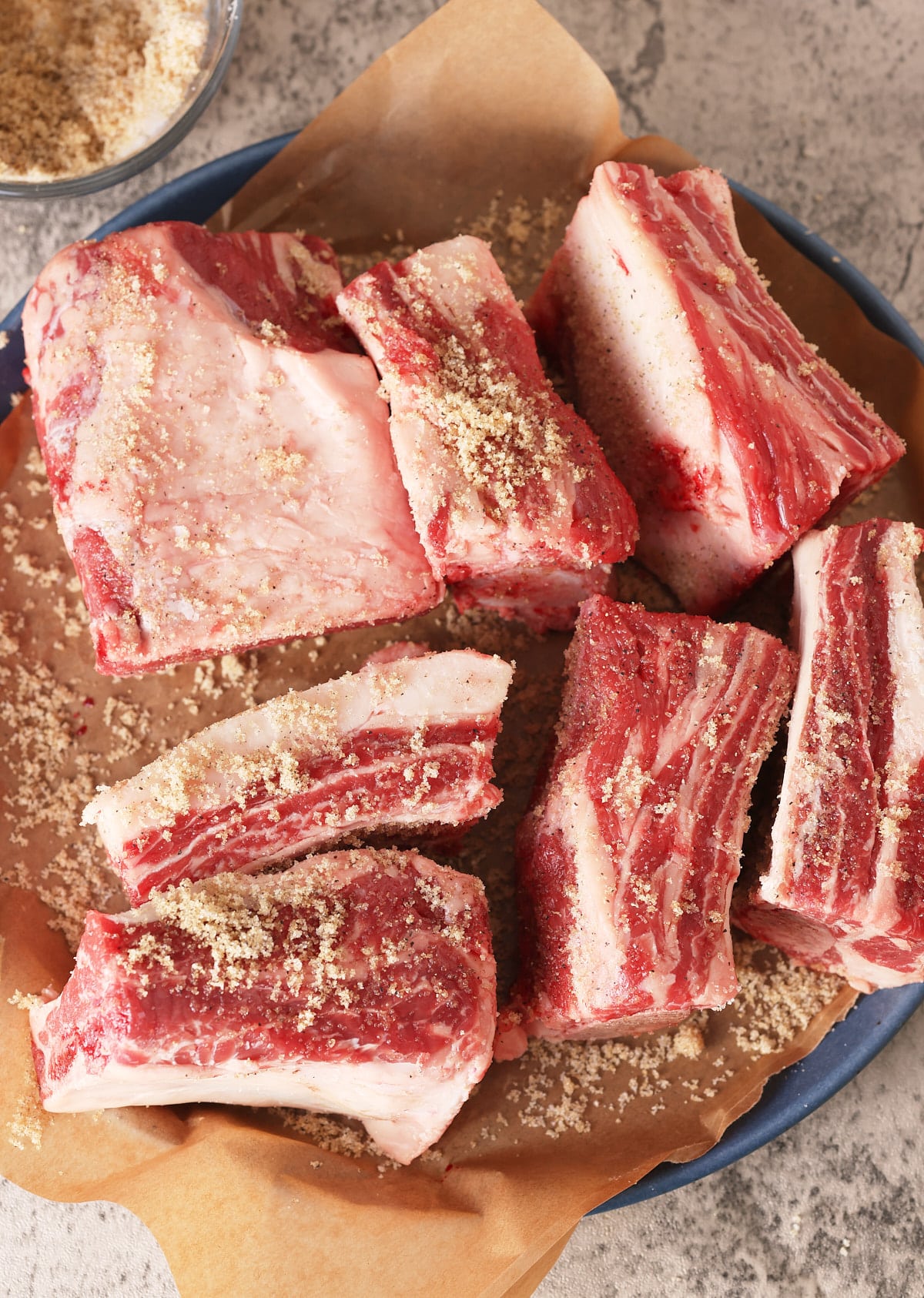 a plate of raw beef short ribs seasoned with brown sugar, salt and black pepper