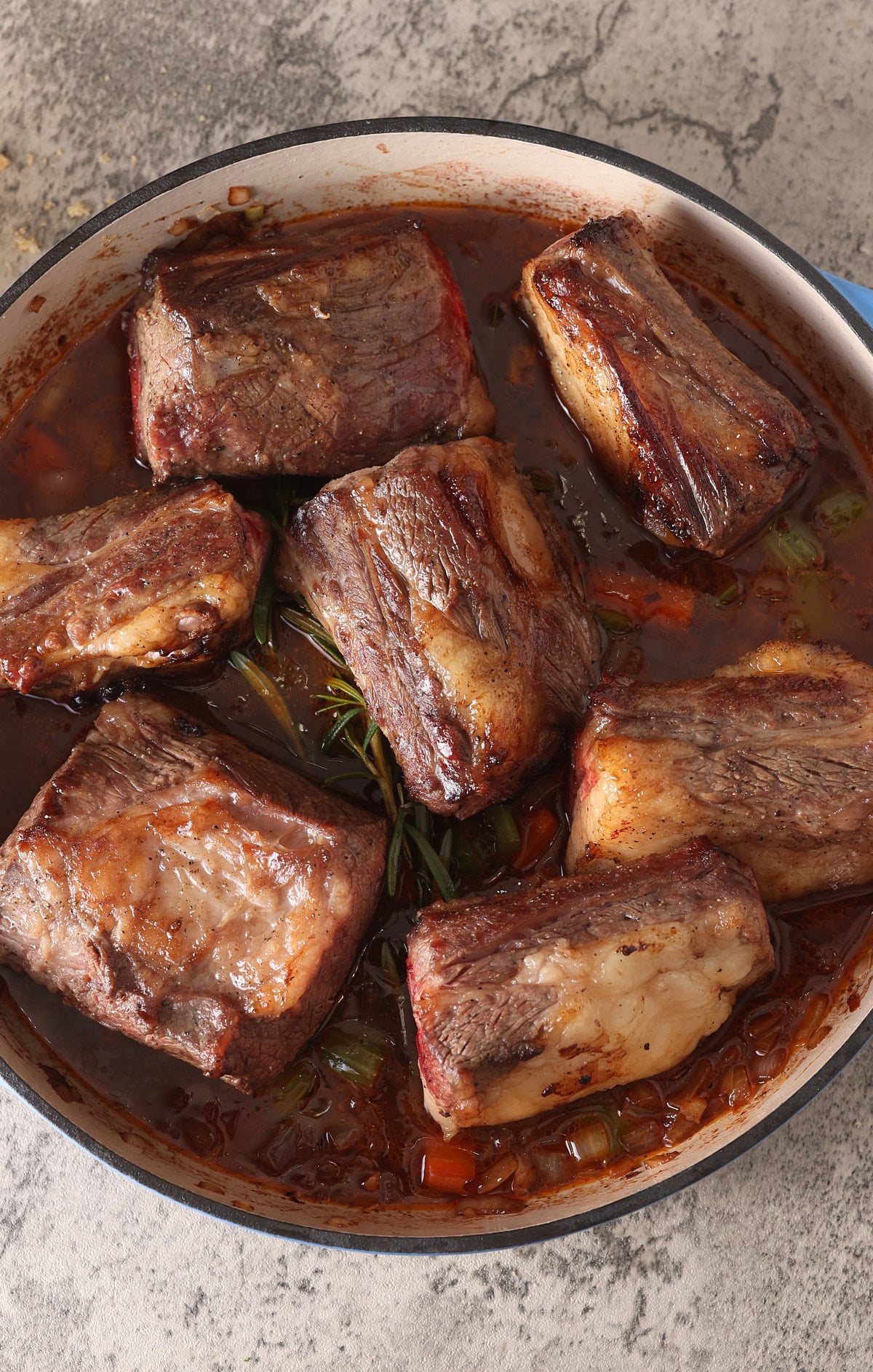 Dutch oven with sauteed vegetables topped with browned beef short ribs