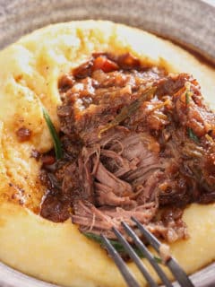 braised beef short rib served on top of a bowl of creamy polenta