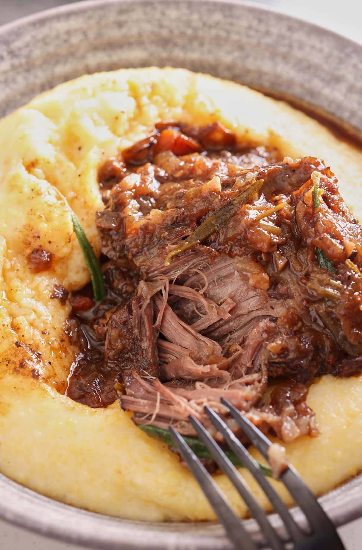 braised beef short rib served on top of a bowl of creamy polenta