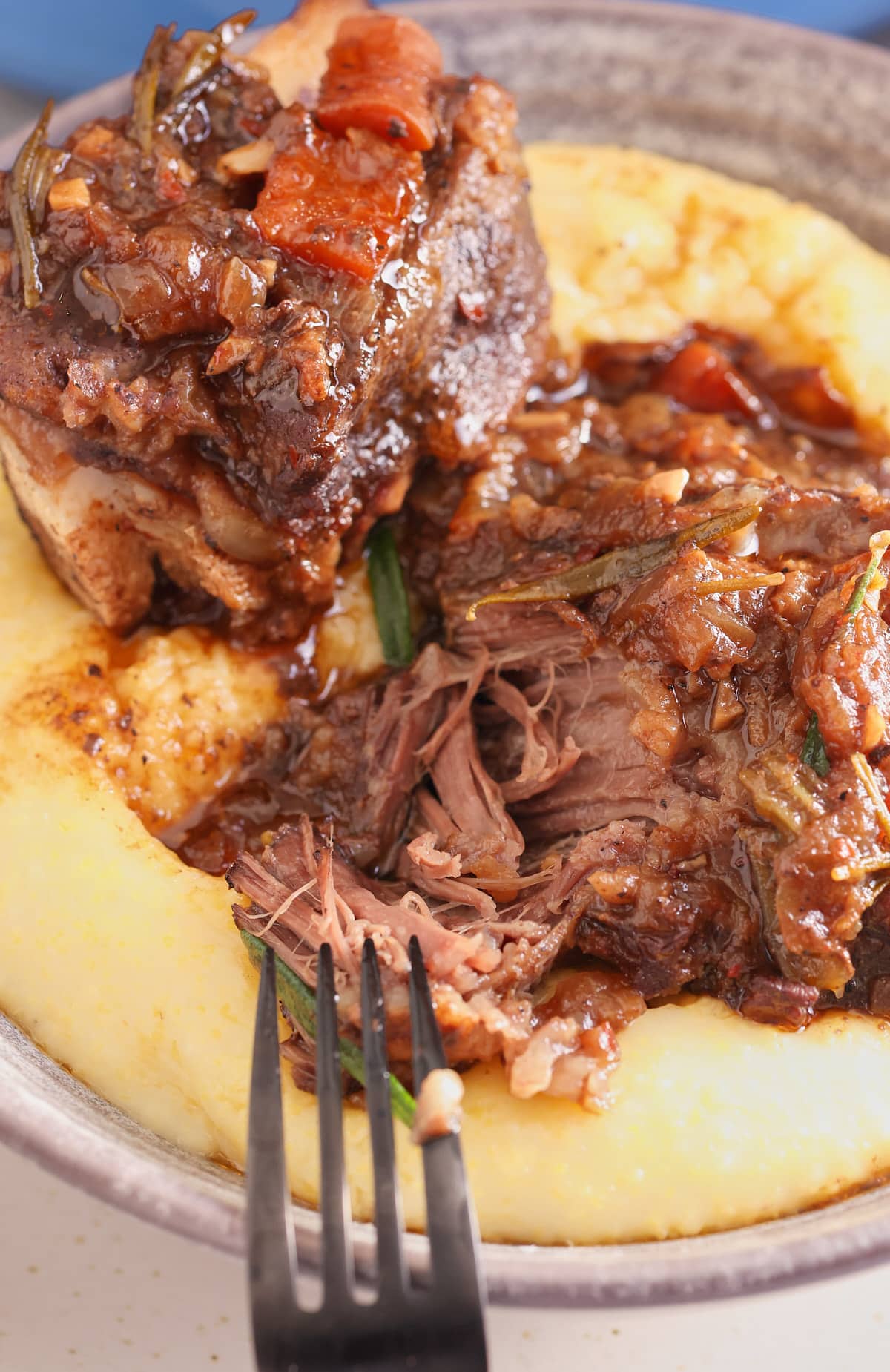 fork tender braised short ribs served on top of a bowl of creamy polenta