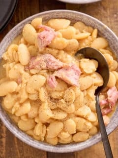 spoon and bowl filled with butter beans, topped with shredded smoked turkey