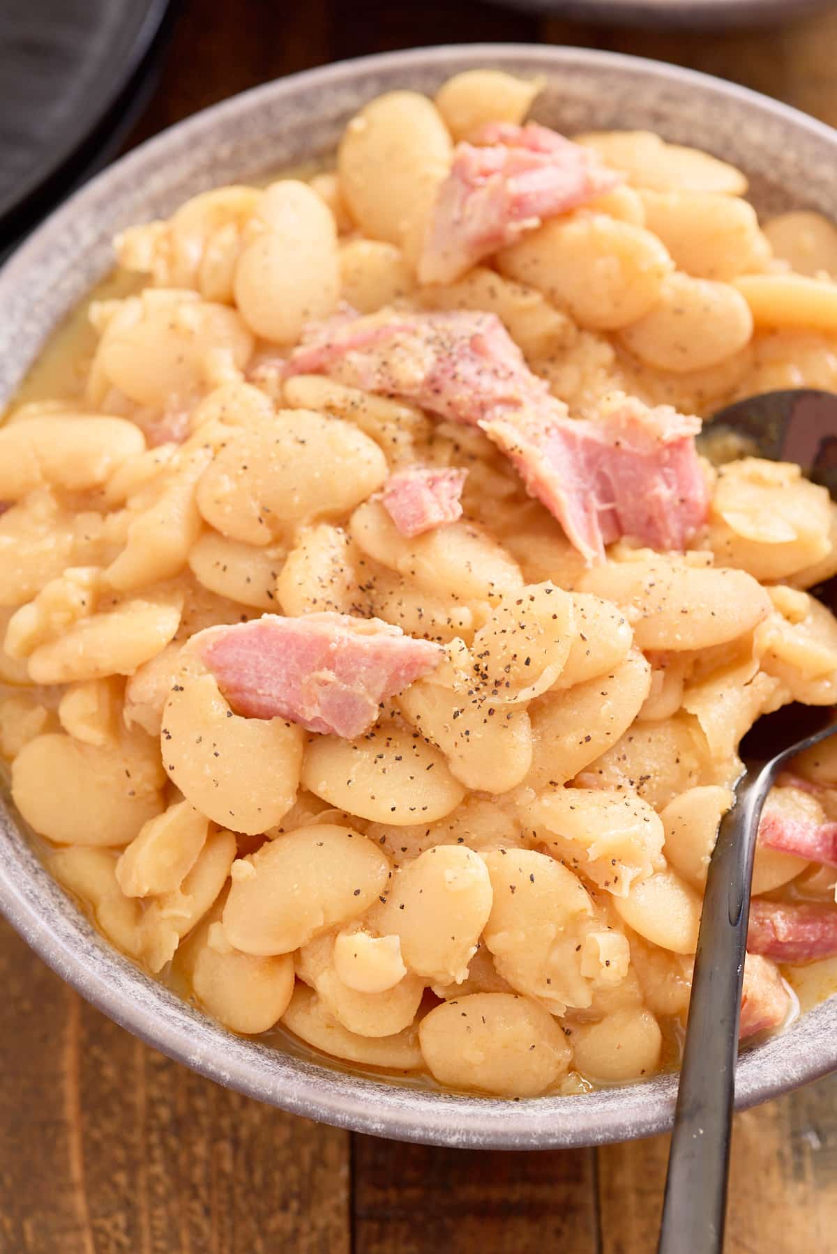 spoon and bowl filled with butter beans, topped with shredded smoked turkey