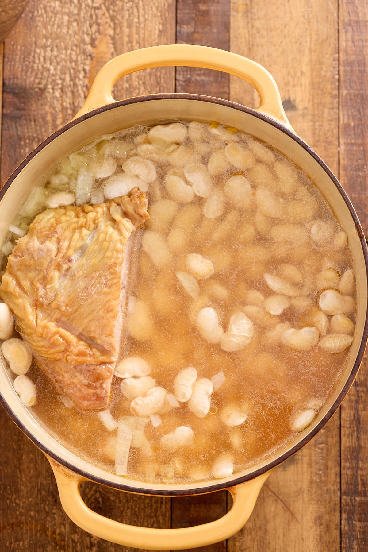 Dutch oven filled with butter beans, turkey drumstick and chicken broth