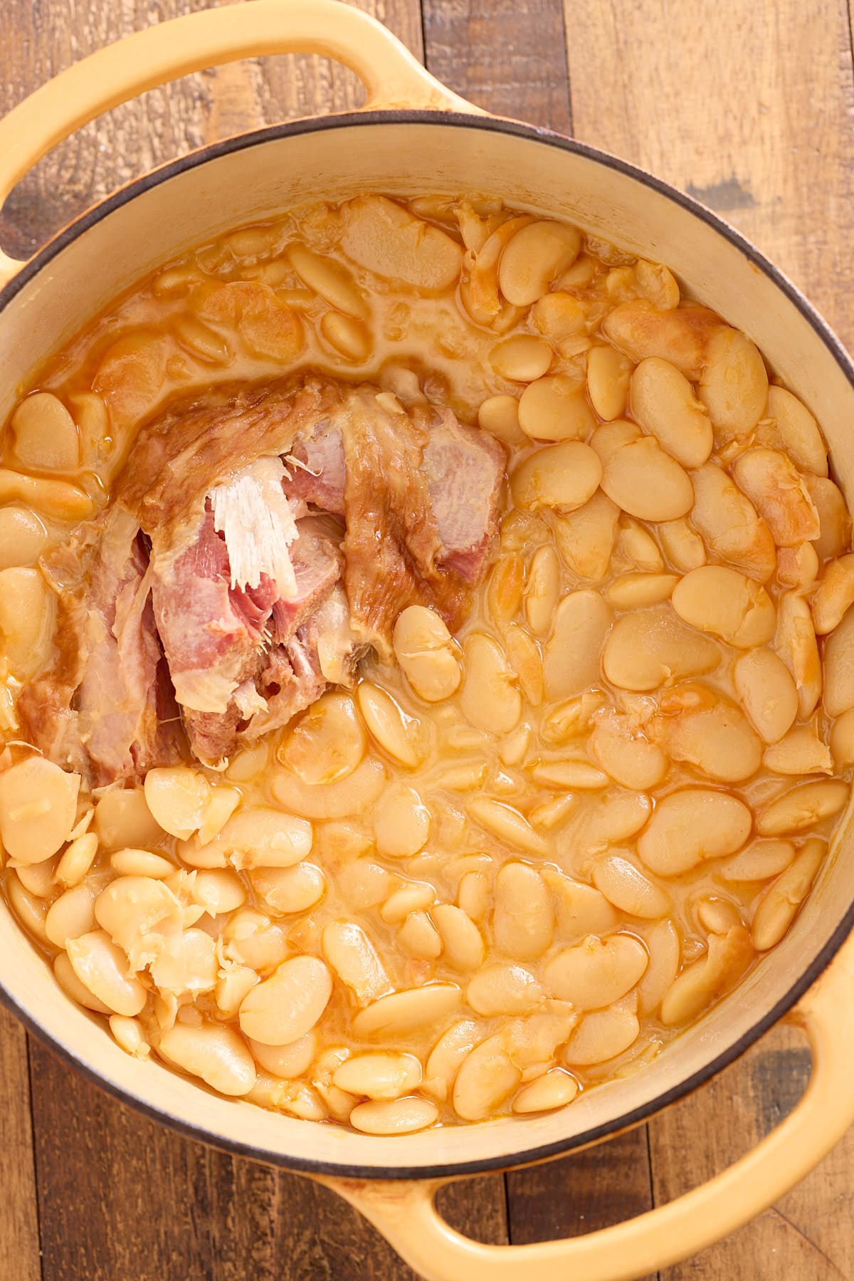 Dutch oven filled with cooked butterbeans and smoked turkey drumstick