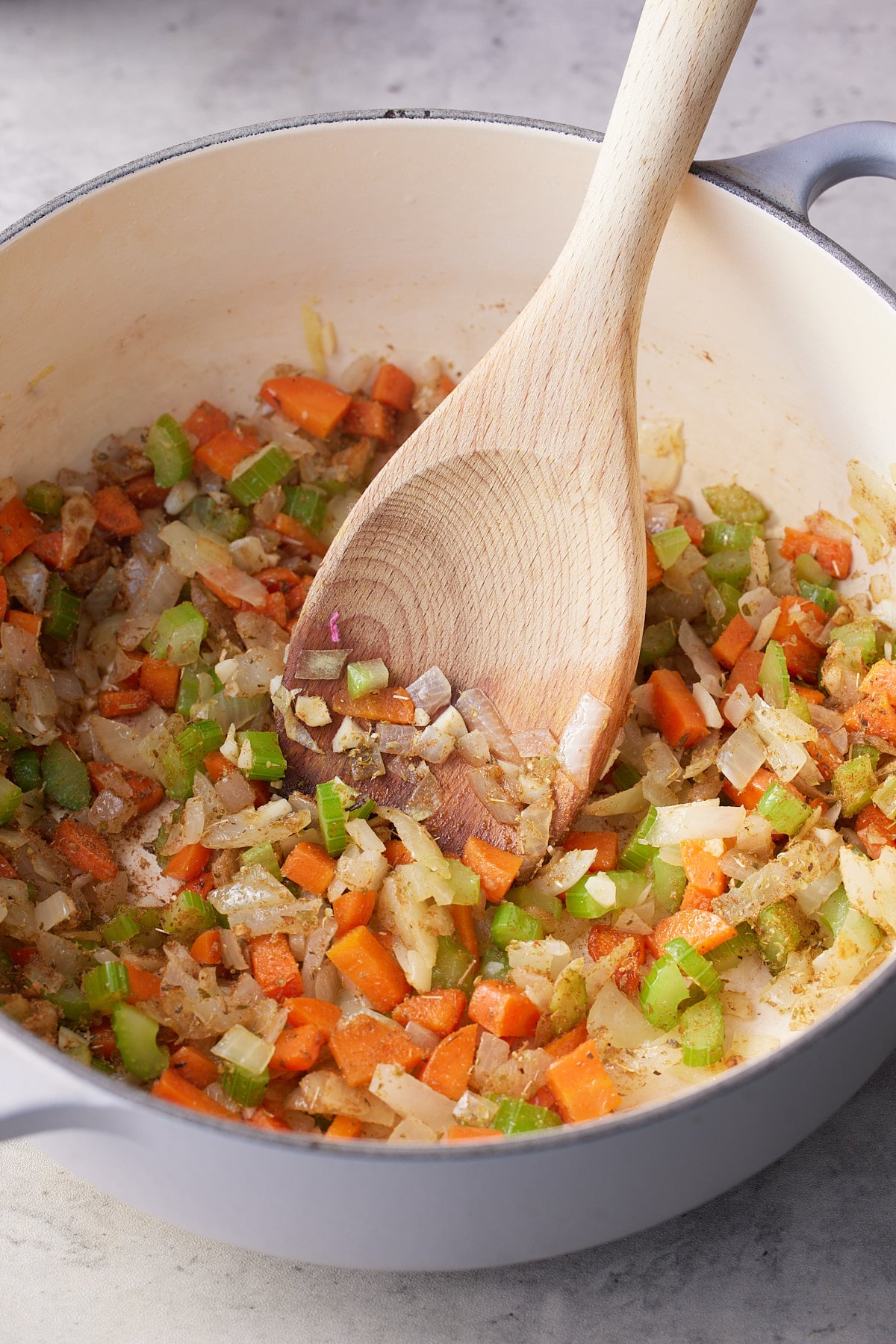 Vegetables and seasonings sauteing in a dutch oven.